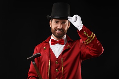 Photo of Portrait of showman in red costume and hat on black background