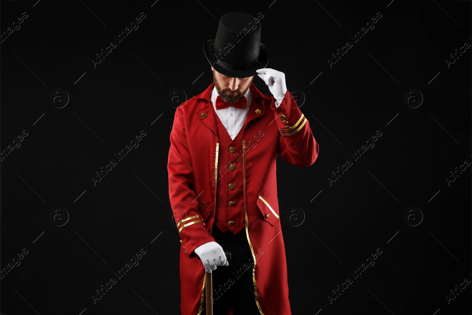 Photo of Portrait of showman in red costume and hat on black background