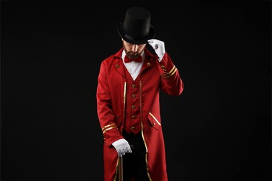 Photo of Portrait of showman in red costume and hat on black background