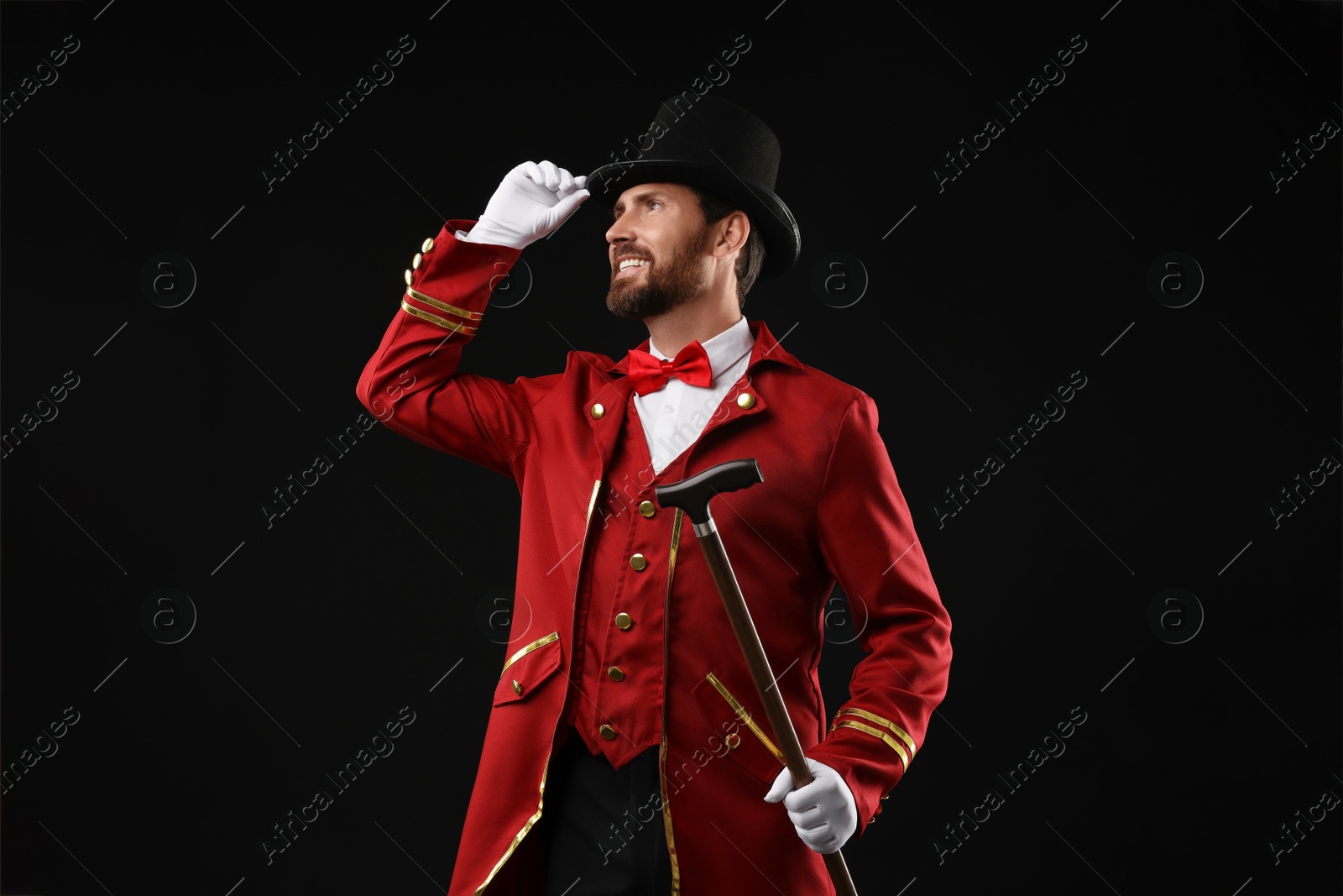 Photo of Portrait of showman in red costume and hat on black background