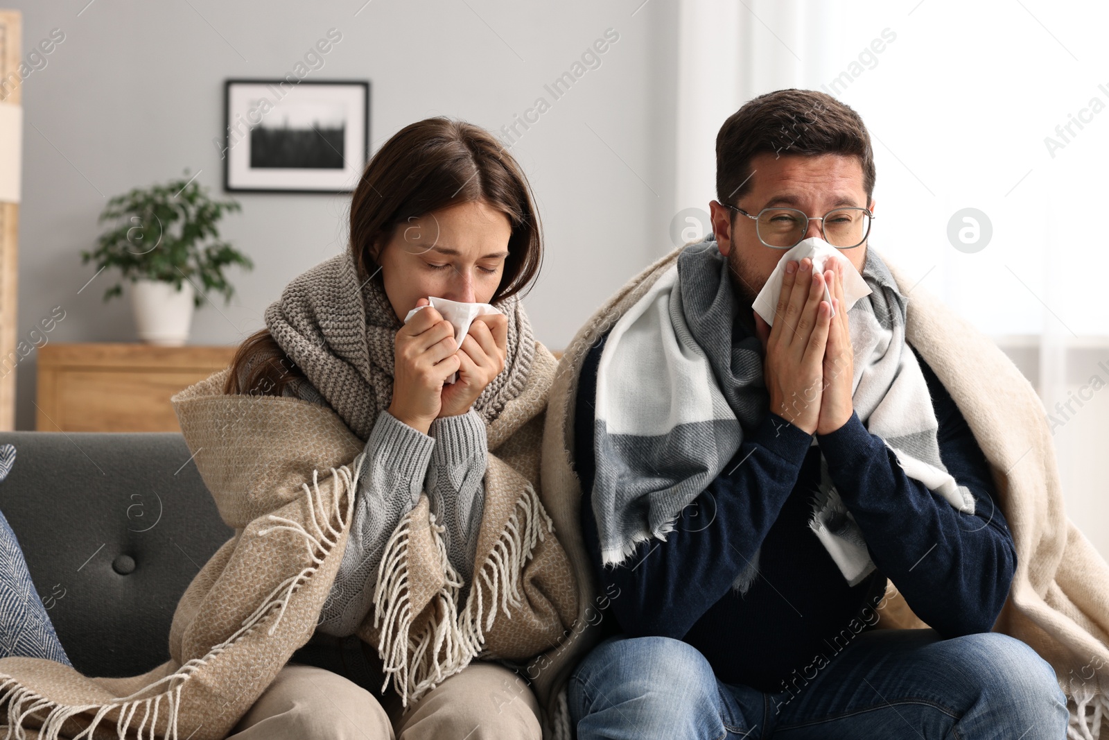 Photo of Cold symptom. Couple suffering from fever on sofa at home