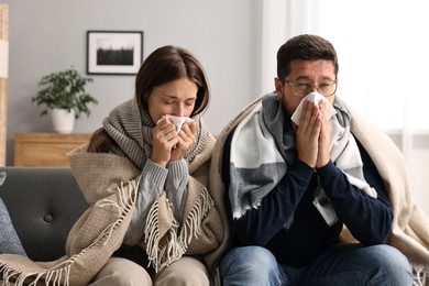 Photo of Cold symptom. Couple suffering from fever on sofa at home