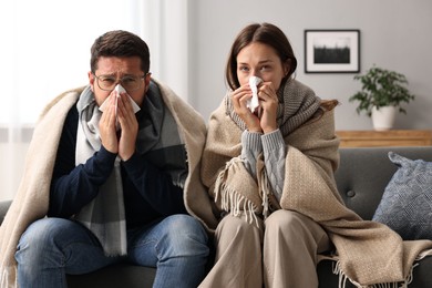 Photo of Cold symptom. Couple suffering from fever on sofa at home