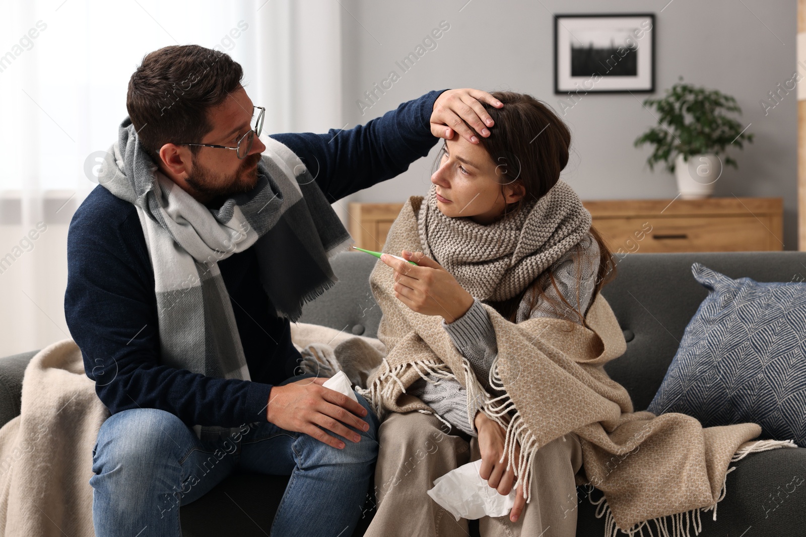 Photo of Cold symptom. Couple suffering from fever on sofa at home