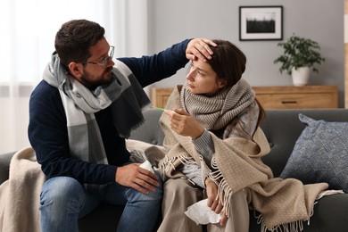 Photo of Cold symptom. Couple suffering from fever on sofa at home