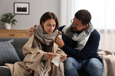 Photo of Cold symptom. Couple suffering from fever on sofa at home