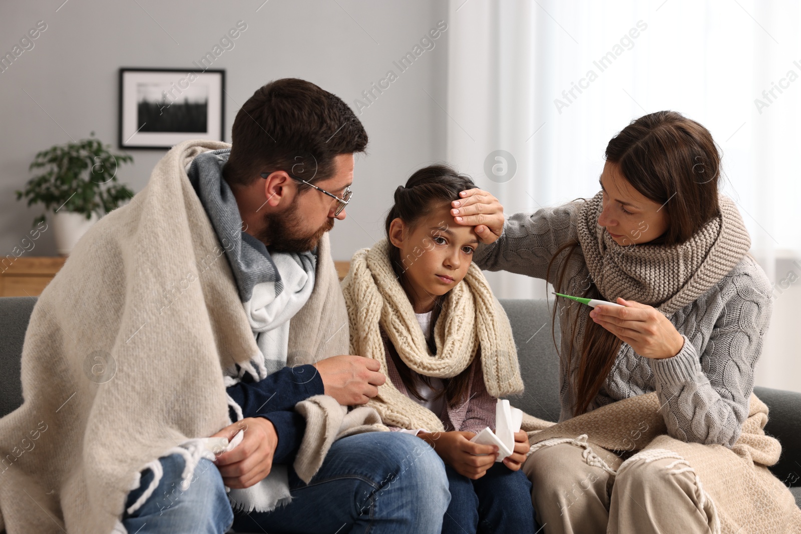 Photo of Cold symptom. Family suffering from fever on sofa at home