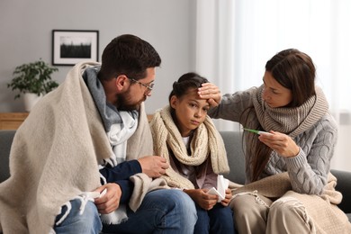 Cold symptom. Family suffering from fever on sofa at home