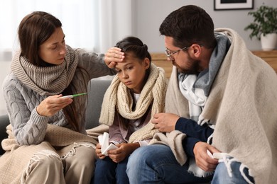 Cold symptom. Family suffering from fever on sofa at home