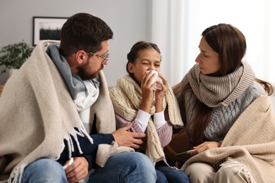 Cold symptom. Family suffering from fever on sofa at home