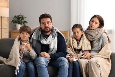 Cold symptom. Family suffering from fever on sofa at home