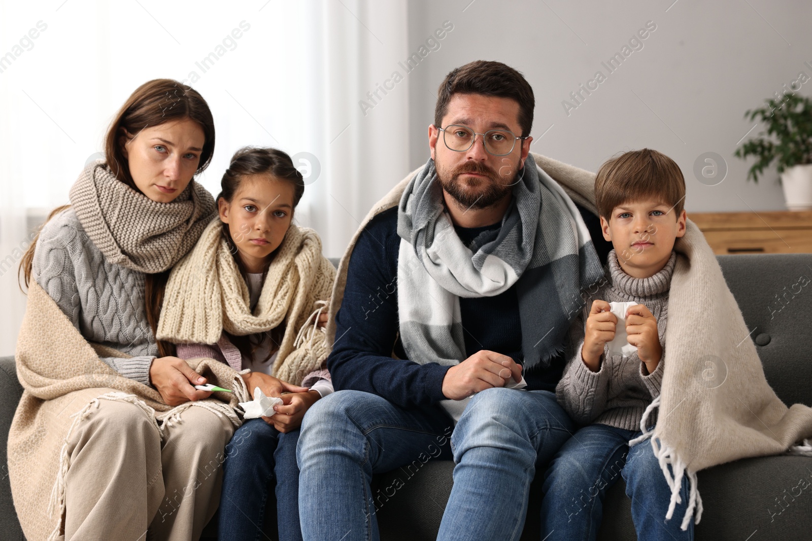 Photo of Cold symptom. Family suffering from fever on sofa at home