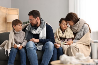 Photo of Cold symptom. Family suffering from fever on sofa at home