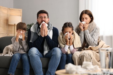 Photo of Cold symptom. Family suffering from fever on sofa at home