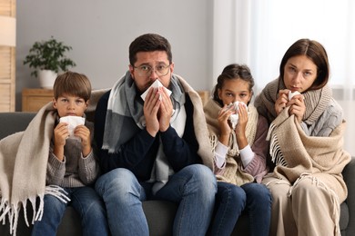 Photo of Cold symptom. Family suffering from fever on sofa at home