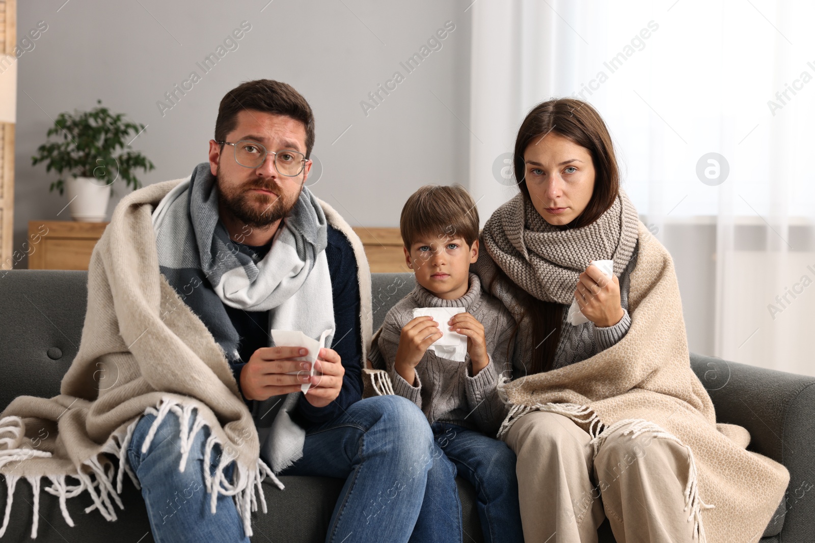 Photo of Cold symptom. Family suffering from fever on sofa at home