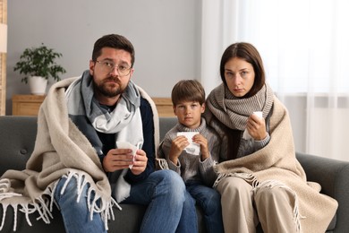 Cold symptom. Family suffering from fever on sofa at home