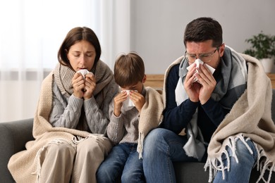 Photo of Cold symptom. Family suffering from fever on sofa at home