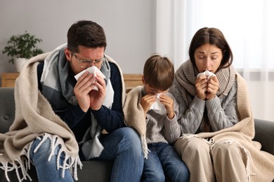 Cold symptom. Family suffering from fever on sofa at home