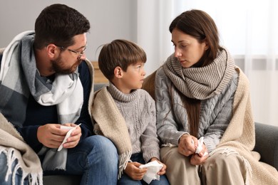 Cold symptom. Family suffering from fever on sofa at home