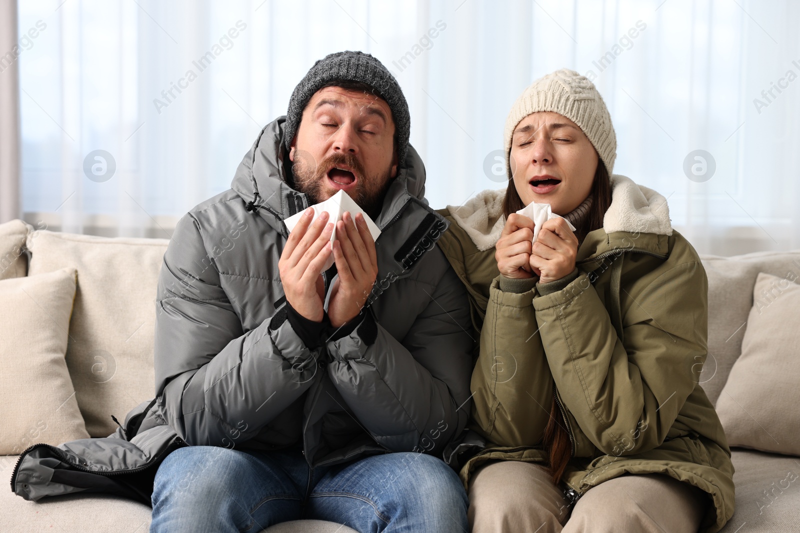 Photo of Cold symptom. Couple suffering from fever on sofa at home