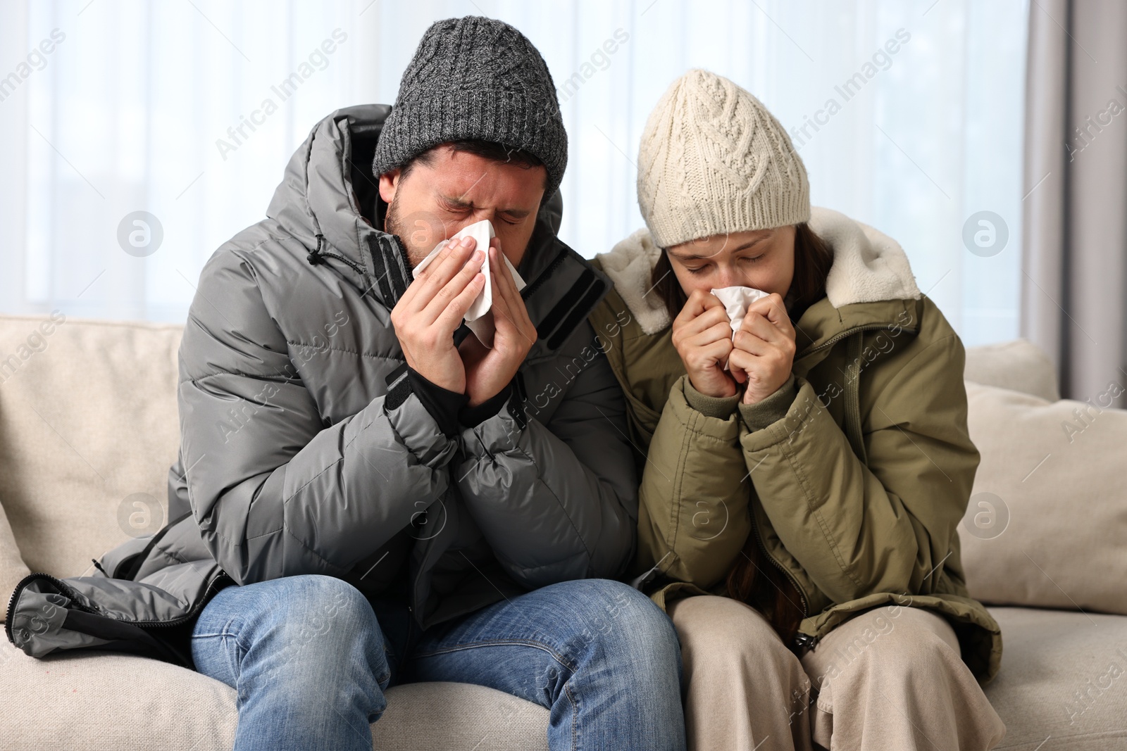 Photo of Cold symptom. Couple suffering from fever on sofa at home