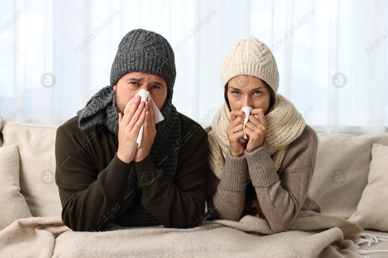 Photo of Cold symptom. Couple suffering from fever on sofa at home