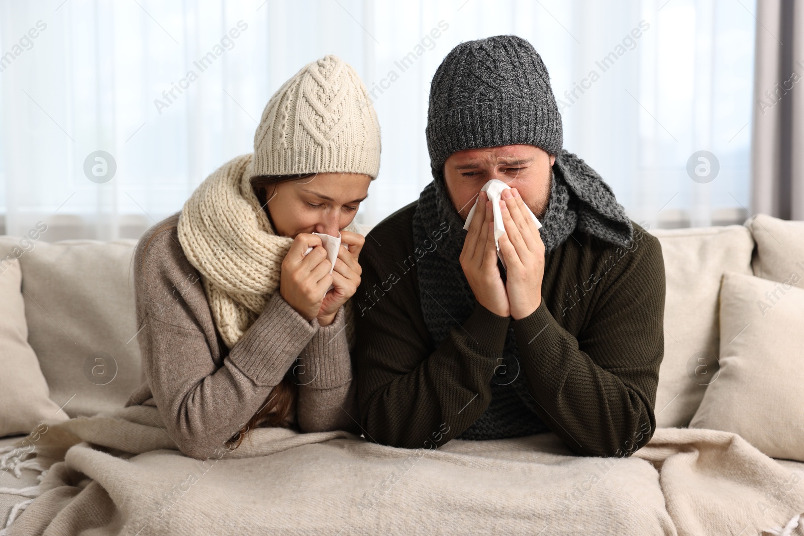 Photo of Cold symptom. Couple suffering from fever on sofa at home