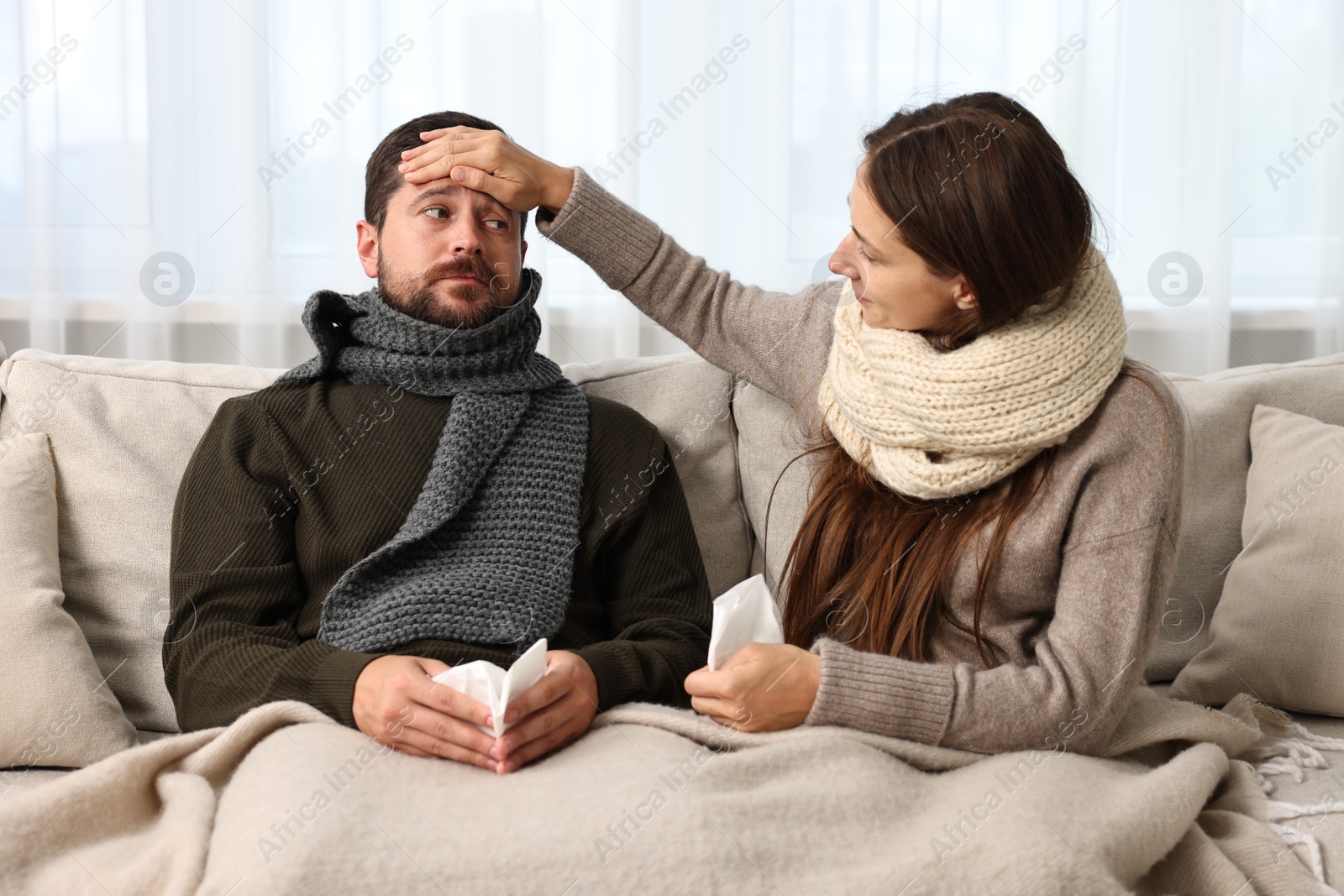 Photo of Cold symptom. Couple suffering from fever on sofa at home