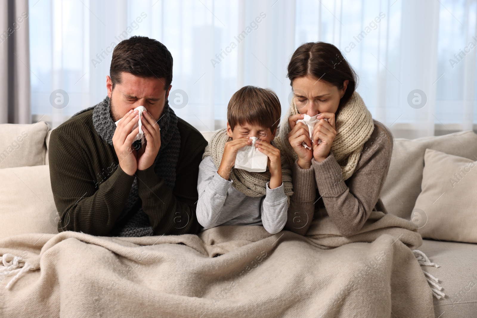 Photo of Cold symptom. Family suffering from fever on sofa at home