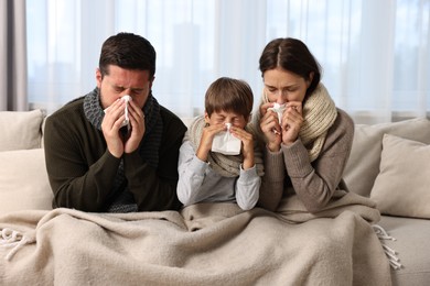 Cold symptom. Family suffering from fever on sofa at home