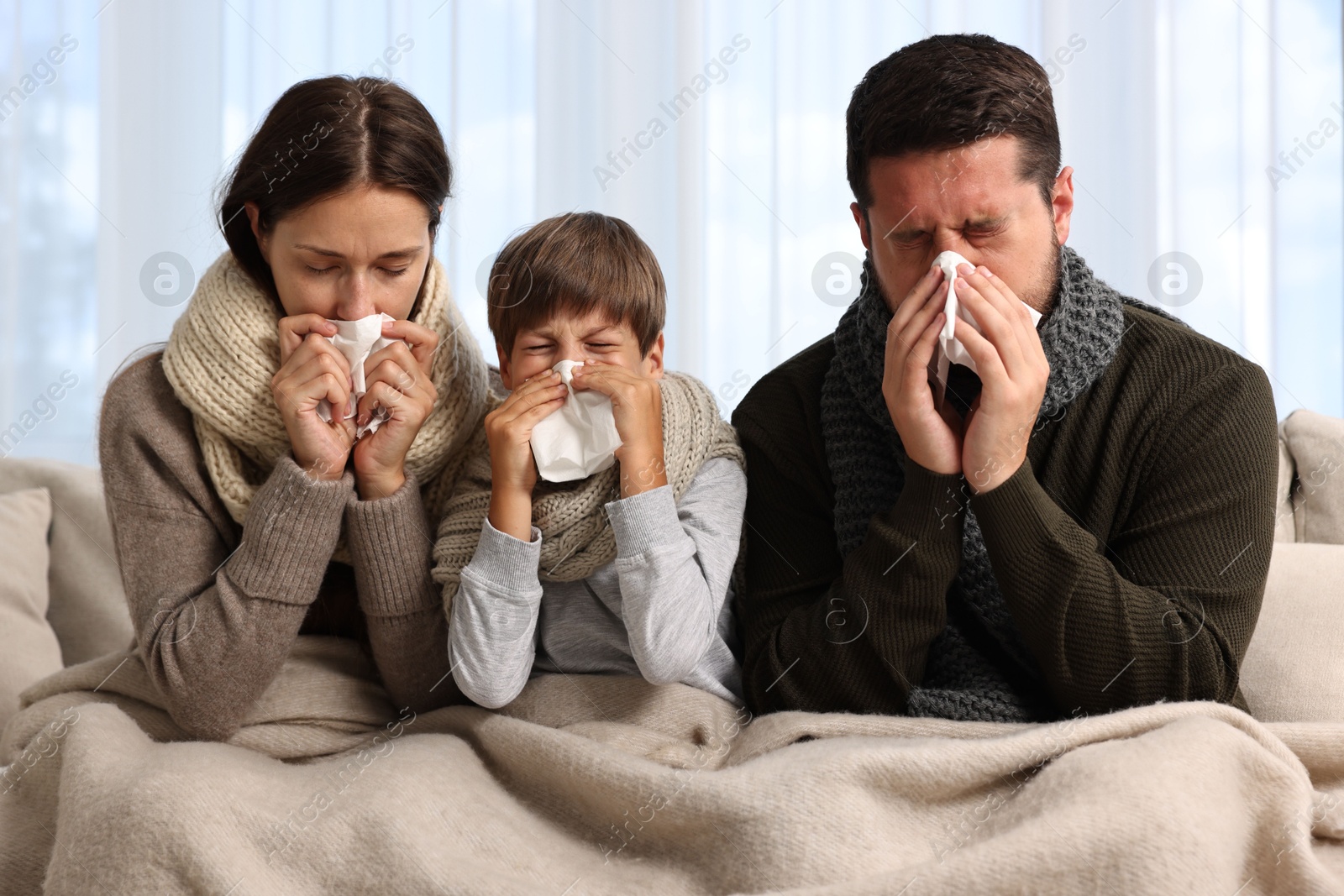 Photo of Cold symptom. Family suffering from fever on sofa at home