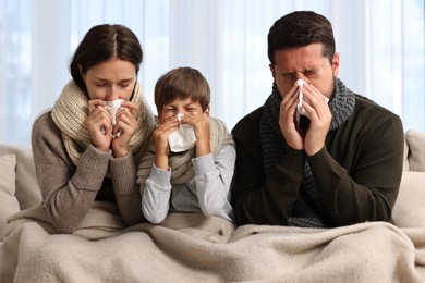 Cold symptom. Family suffering from fever on sofa at home