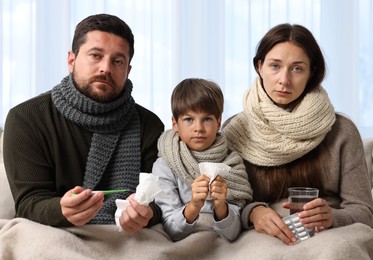 Cold symptom. Family suffering from fever on sofa at home