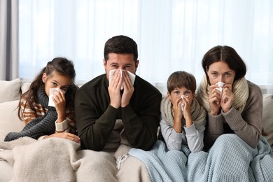 Photo of Cold symptom. Family suffering from fever on sofa at home