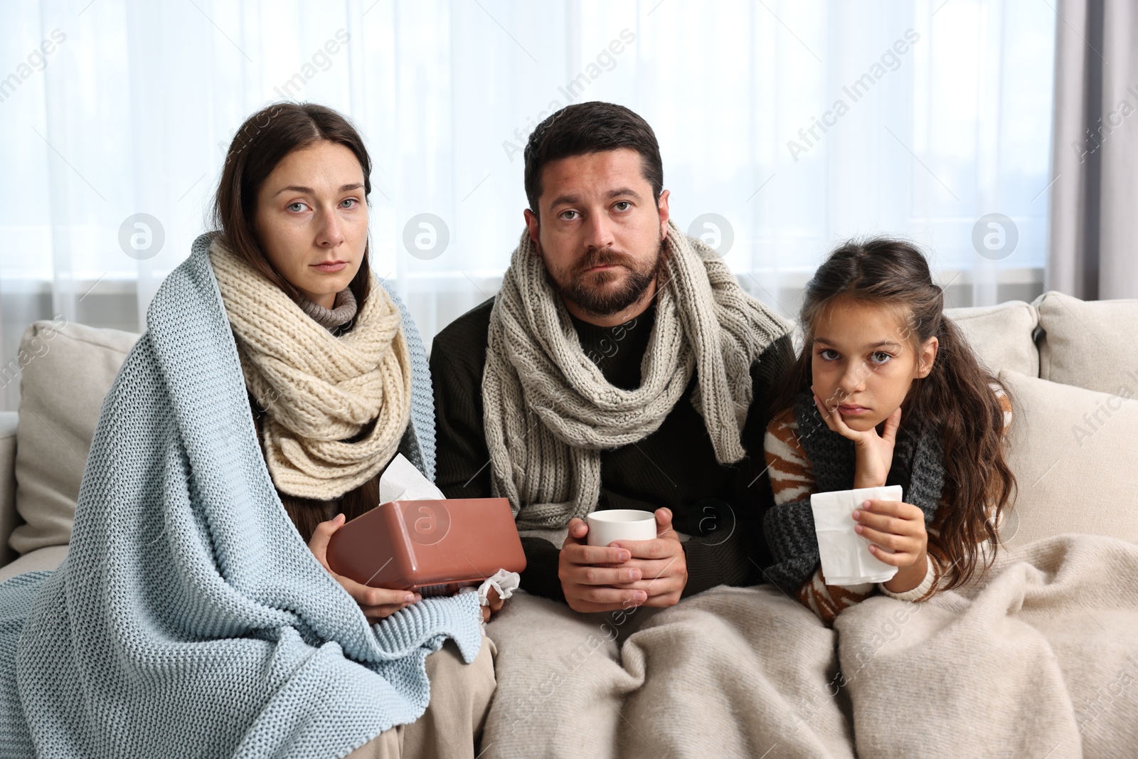 Photo of Cold symptom. Family suffering from fever on sofa at home