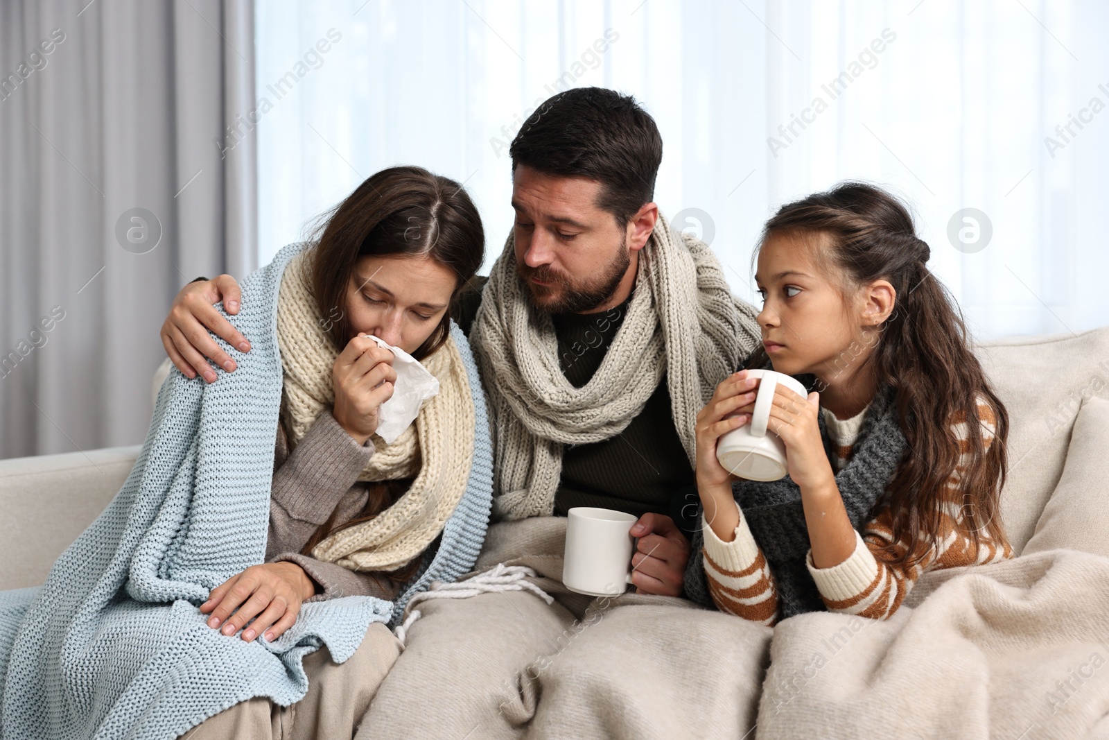 Photo of Cold symptom. Family suffering from fever on sofa at home