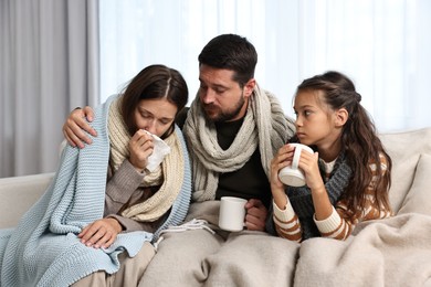 Cold symptom. Family suffering from fever on sofa at home