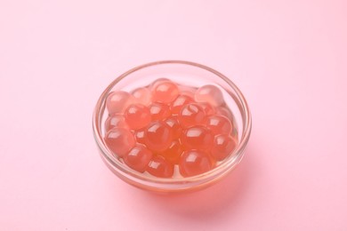 Photo of Bright tapioca pearls in bowl on pink background, closeup