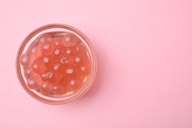 Photo of Bright tapioca pearls in bowl on pink background, top view. Space for text