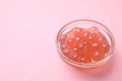 Photo of Bright tapioca pearls in bowl on pink background, closeup. Space for text