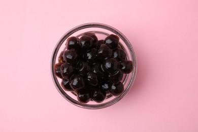 Photo of Dark tapioca pearls in bowl on pink background, top view