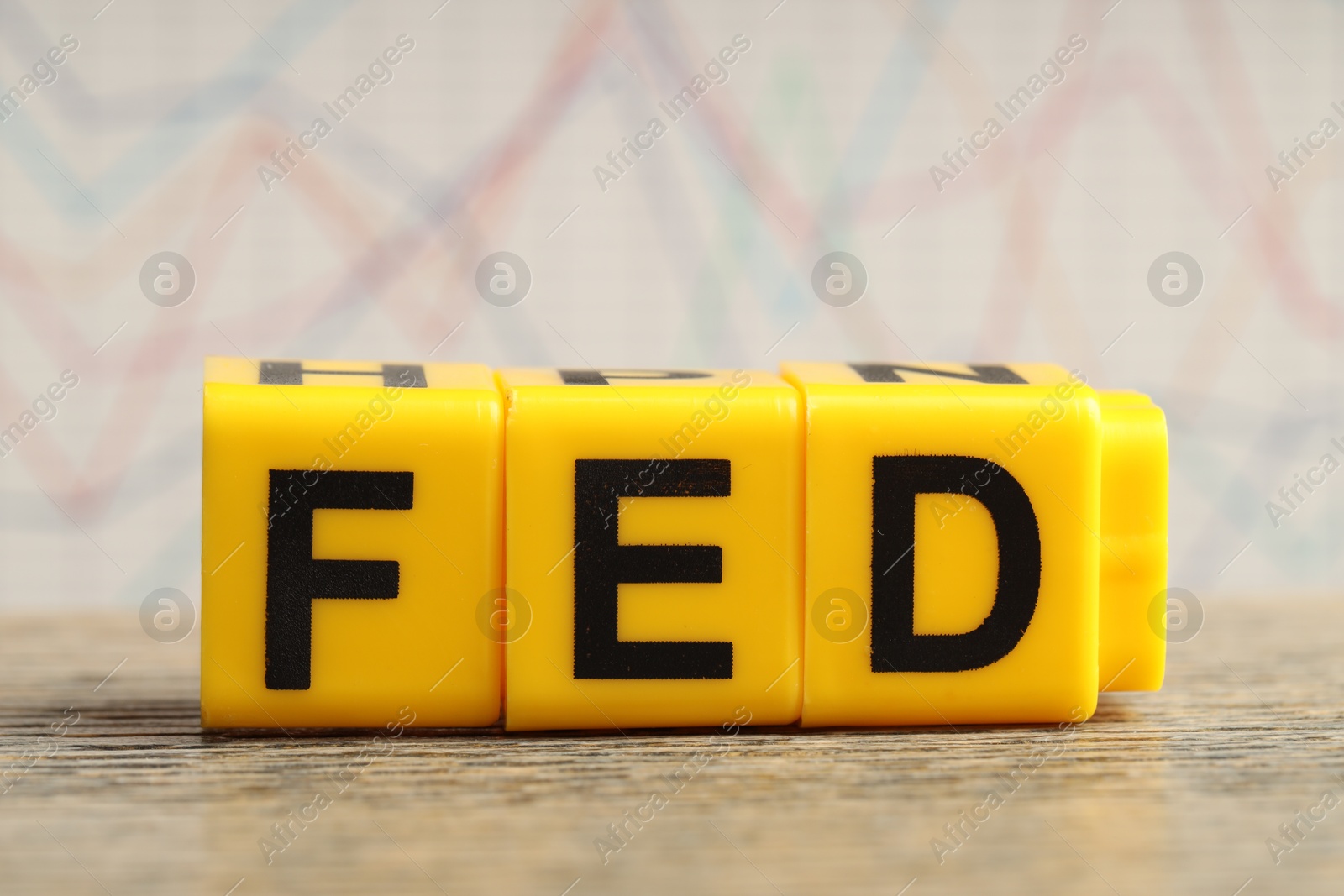 Photo of Cubes with letters Fed (Federal Reserve System) on wooden table, closeup