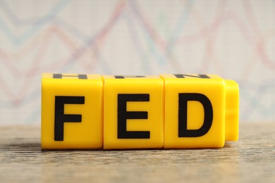 Cubes with letters Fed (Federal Reserve System) on wooden table, closeup