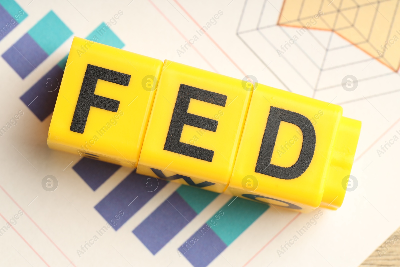 Photo of Cubes with letters Fed (Federal Reserve System) and paper with graphs, top view