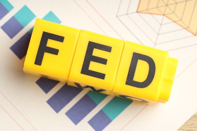 Cubes with letters Fed (Federal Reserve System) and paper with graphs, top view