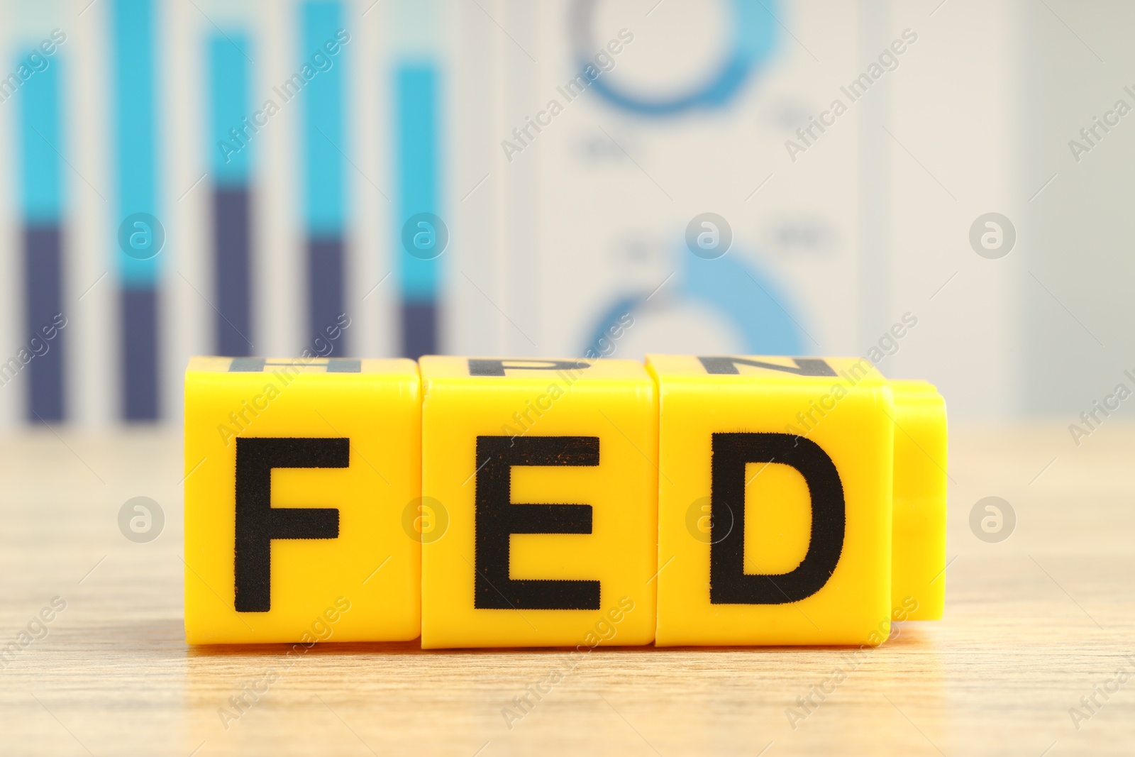 Photo of Cubes with letters Fed (Federal Reserve System) on wooden table, closeup