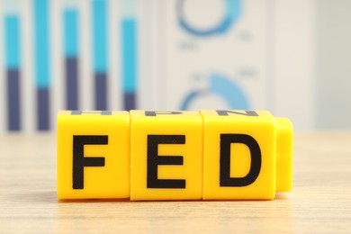 Photo of Cubes with letters Fed (Federal Reserve System) on wooden table, closeup