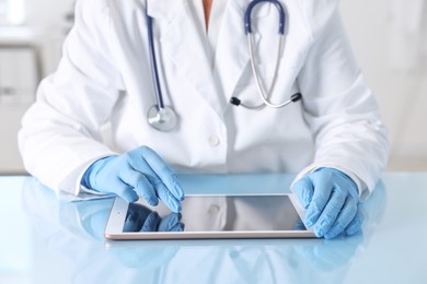 Photo of Doctor with tablet at table in clinic, closeup view