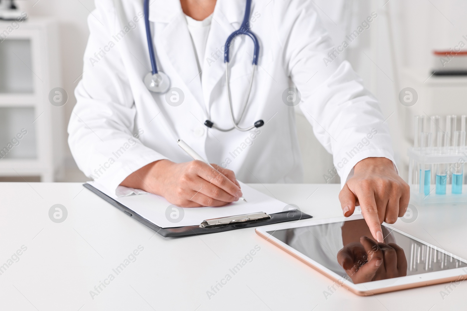 Photo of Doctor with tablet at table in clinic, closeup view